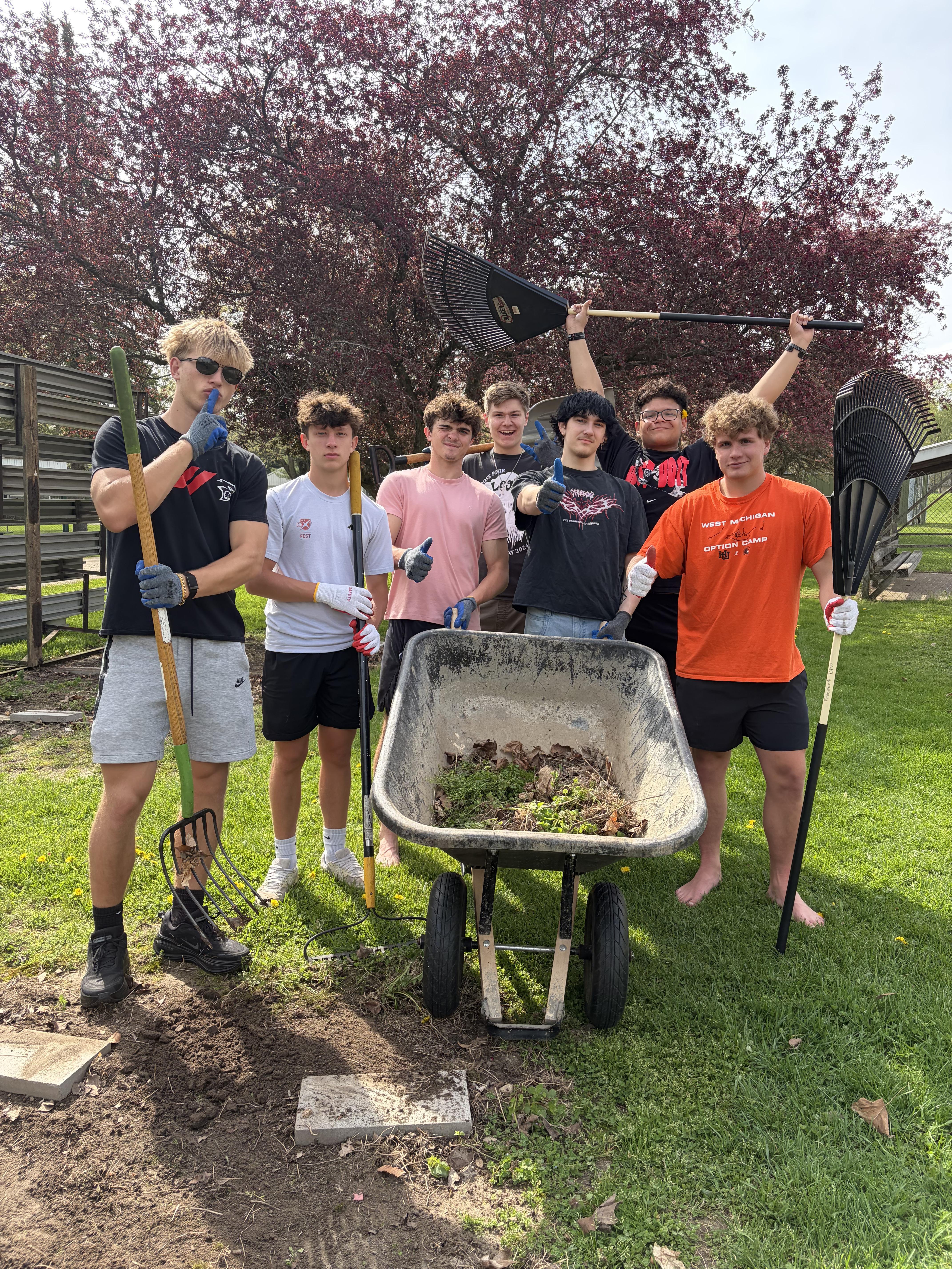 A group of students with rakes and a wheelbarrow clean up a park in Freeport.