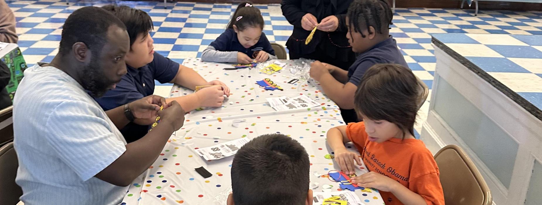 Children crafting with beads at a decorated table.