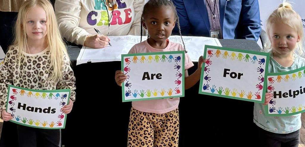 kids holding up signs that say Hands are for Helping