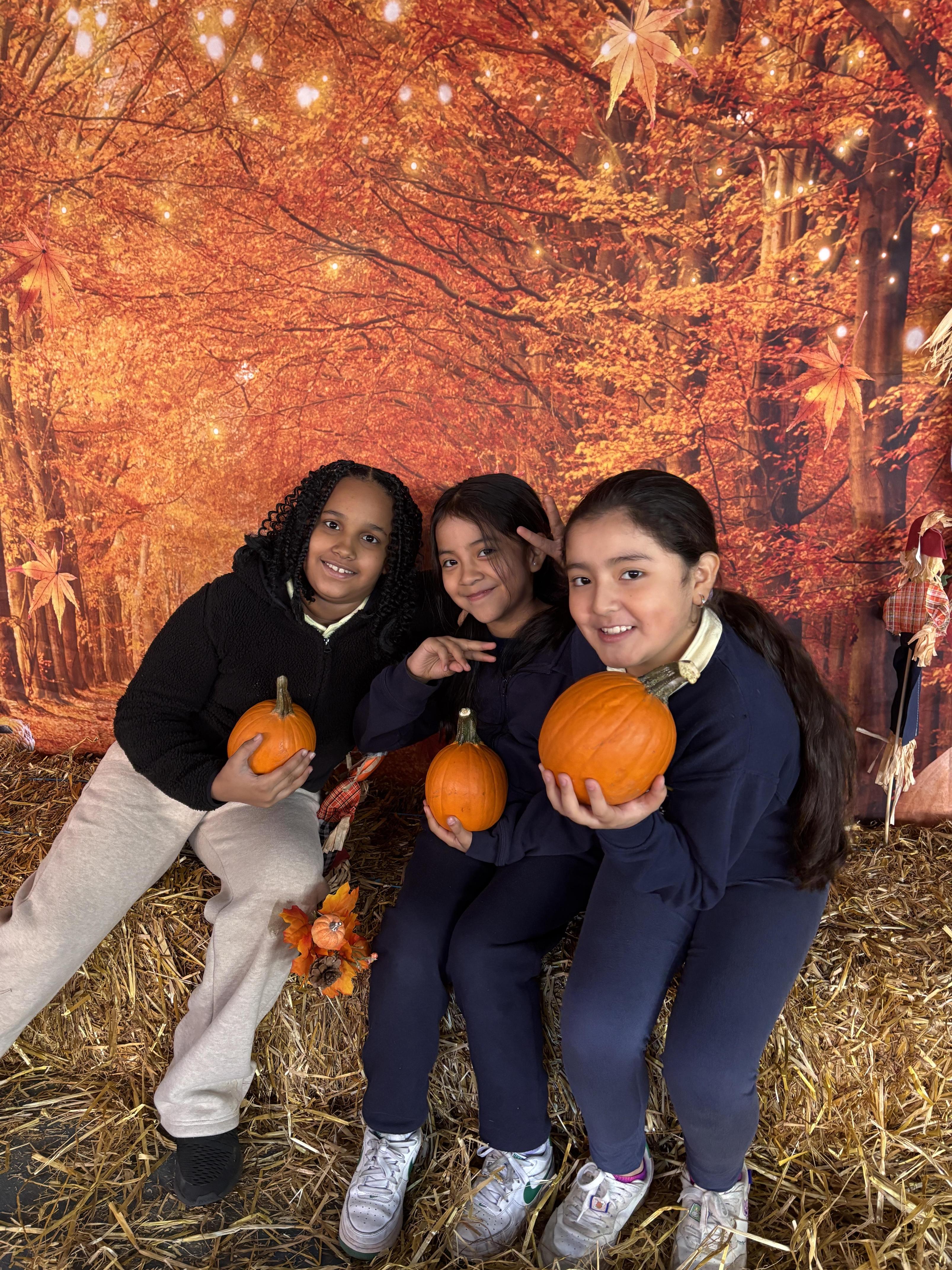 Three students holding pumpkins