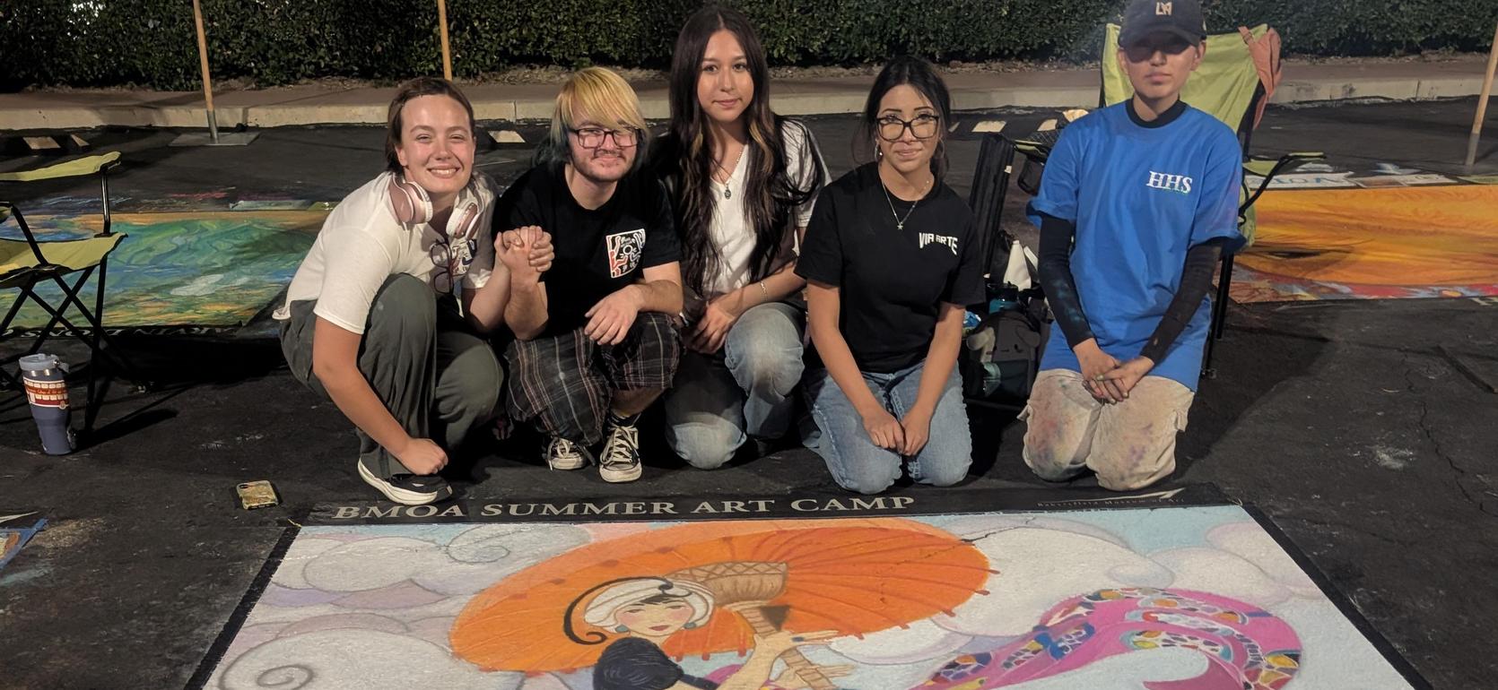 Participants showcasing a chalk drawing of a woman with an umbrella at an art camp.