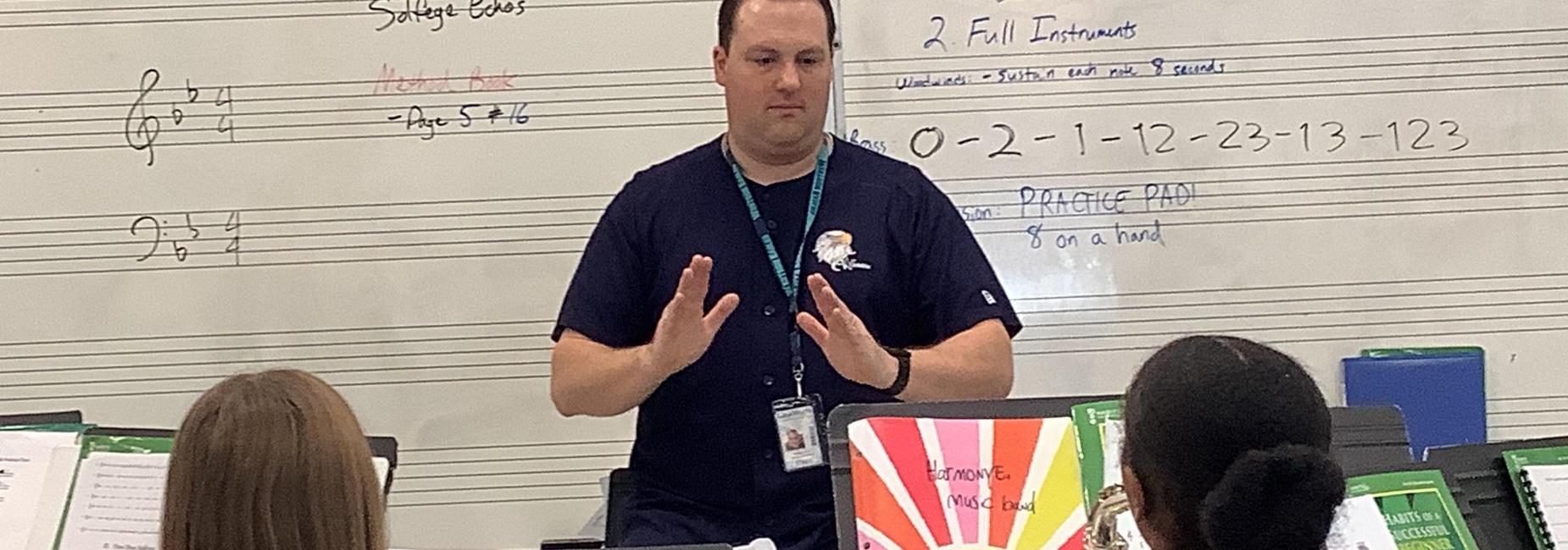 Music teacher conducting a group lesson with students in a classroom.