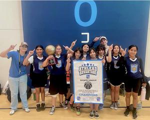 Basketball team poses with Championship banner