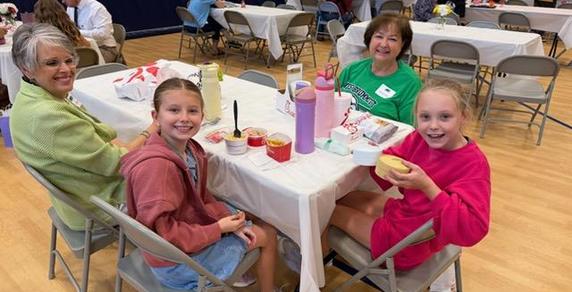 Four people, two adults and two children, sitting at a table with food and drinks.
