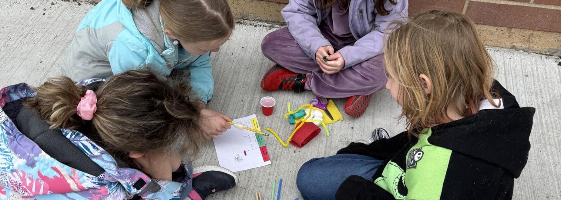 Group of children engaged in an outdoor activity with materials.