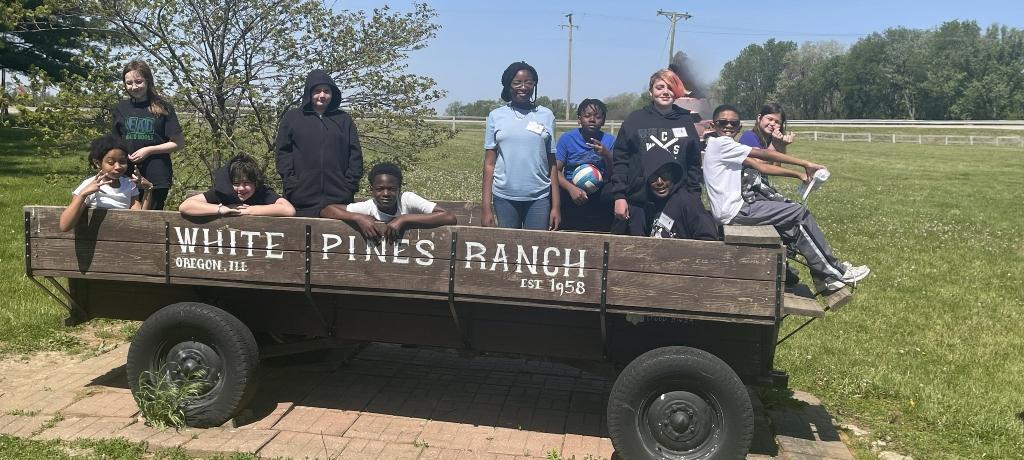 group of students pose for a photo atop the White Pines Ranch horse wagon