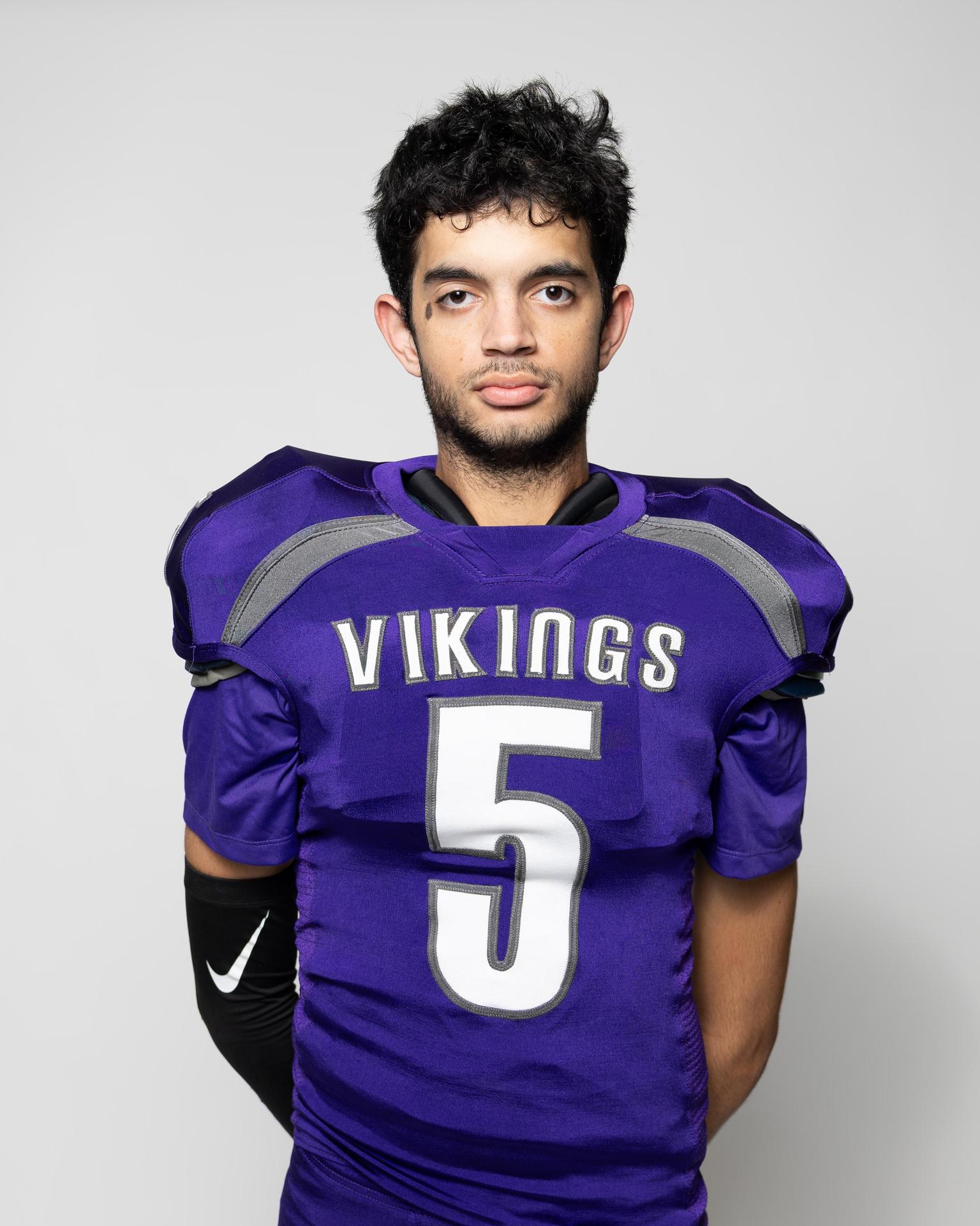 Athlete in a purple football uniform with the number 5, standing confidently.