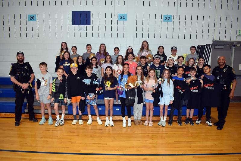 Group of students and police officers posing together in a school gym.