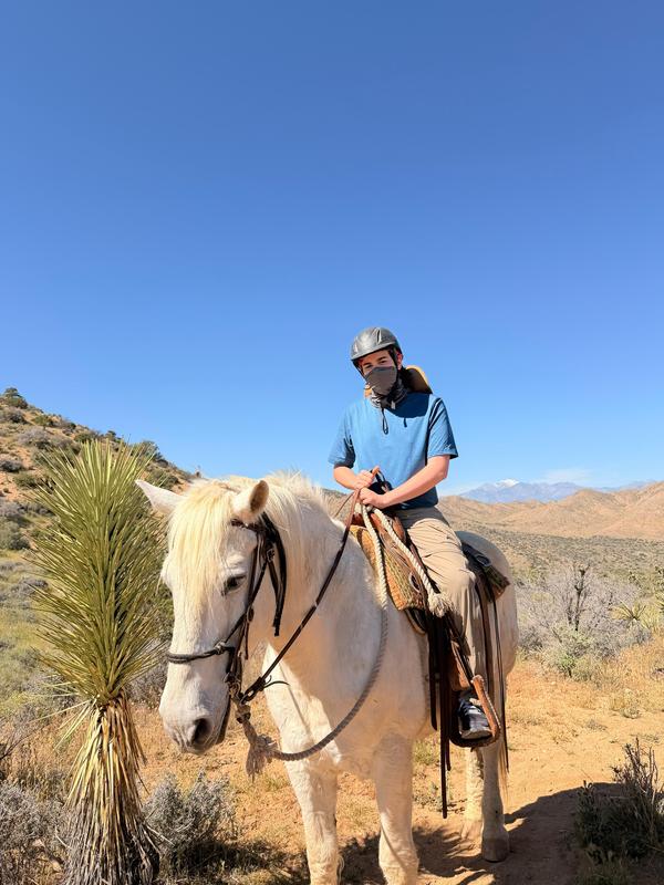 Student riding a horse in the desert