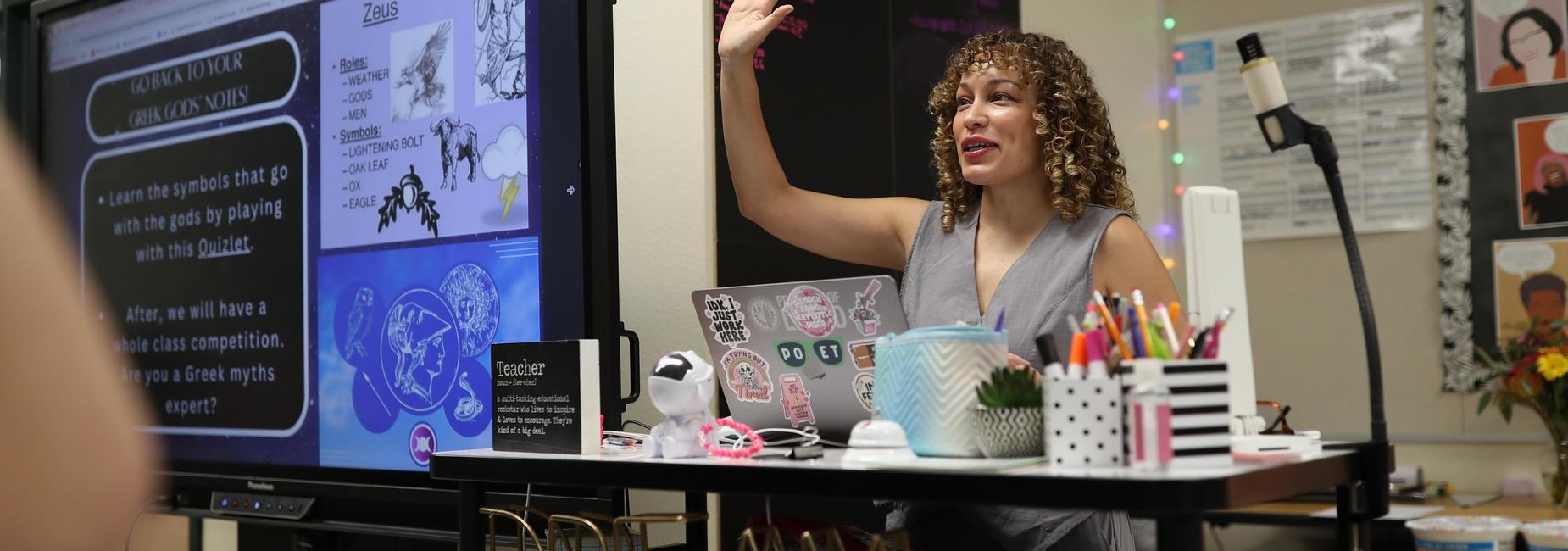Instructor engaging with students while presenting on a screen.