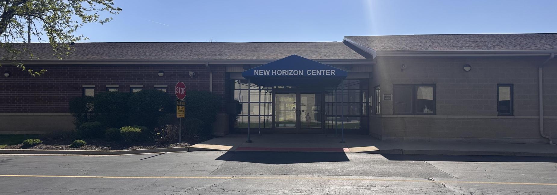 Entrance of New Horizon Center with an awning and clear signage.
