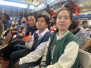 Three individuals sitting in a crowded venue, smiling and engaging with the event.