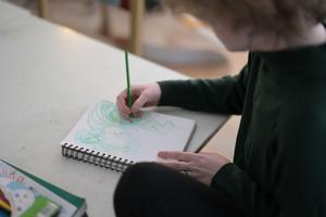 student at tuition-free public charter school HCIS drawing with a green pencil in a sketchbook