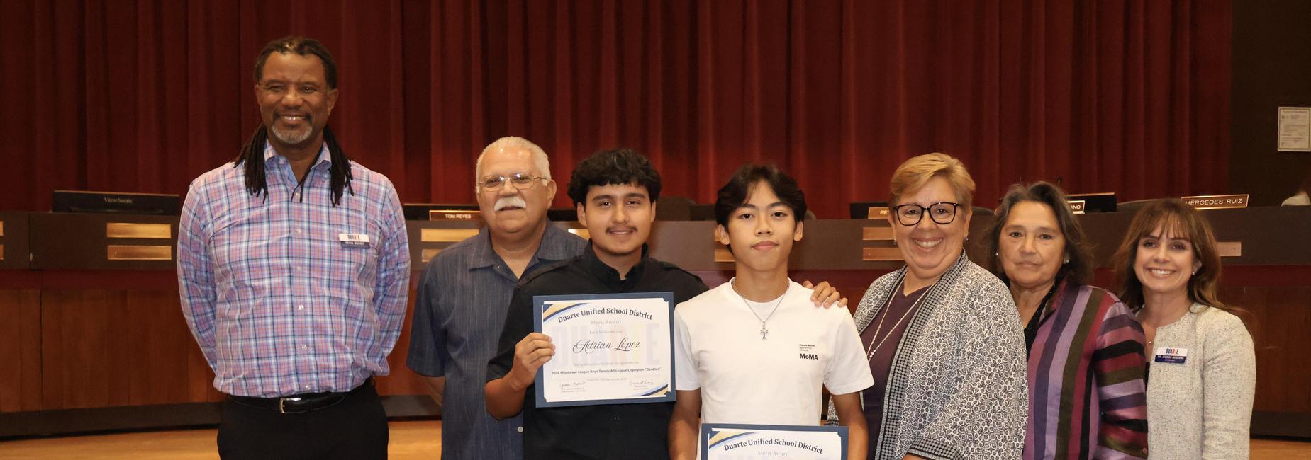 Group of people holding certificates in a formal setting.