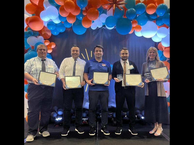 LISA administrators stand with their awards in front of a blue and red balloon backdrop