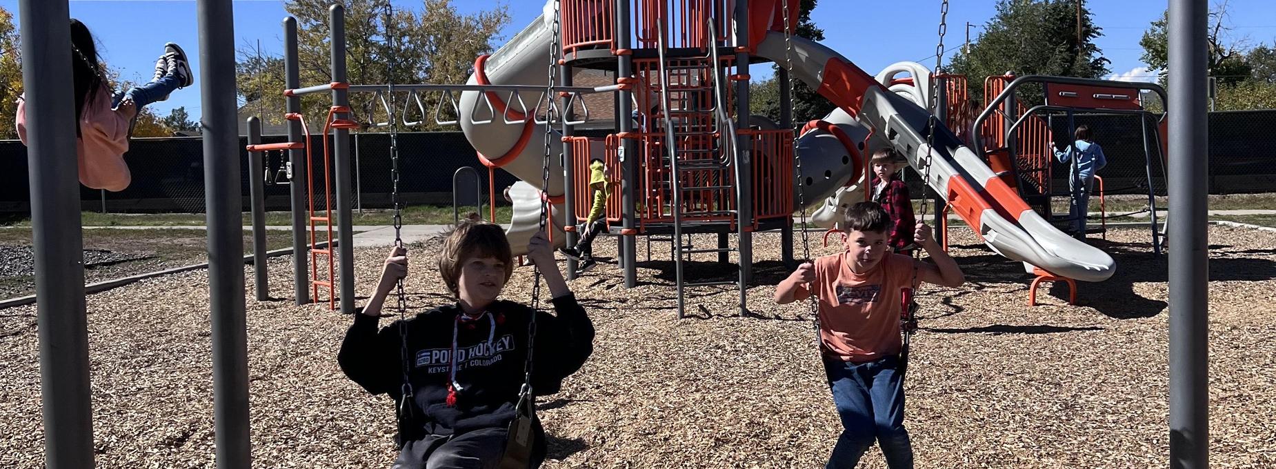 Children enjoy playing on a colorful playground with swings and slides.