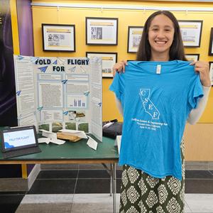 Student at Science Fair holding blue event t-shirt
