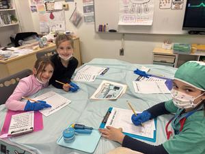 Second grade girls pause in the middle performing "surgery"