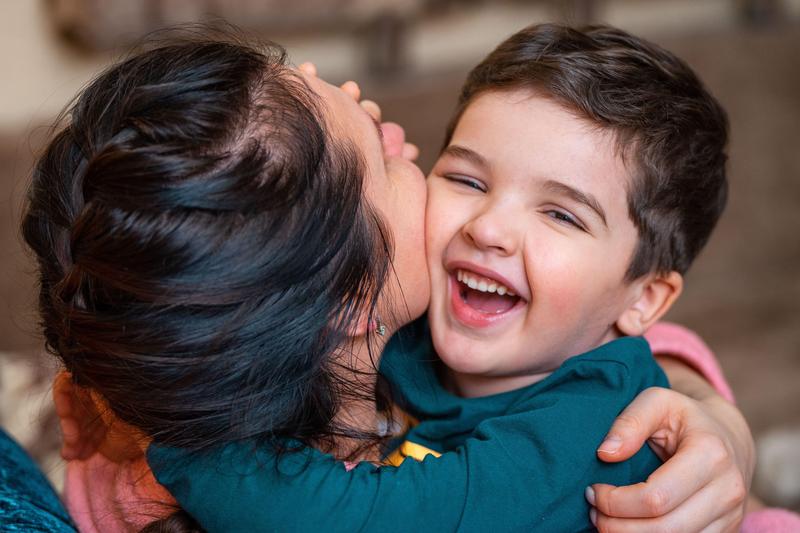Close-up of a joyful mother and child embracing indoors, filled with warmth and happiness