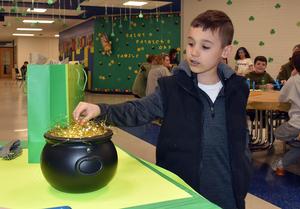 a boy putting a coin in a pot of gold decoration