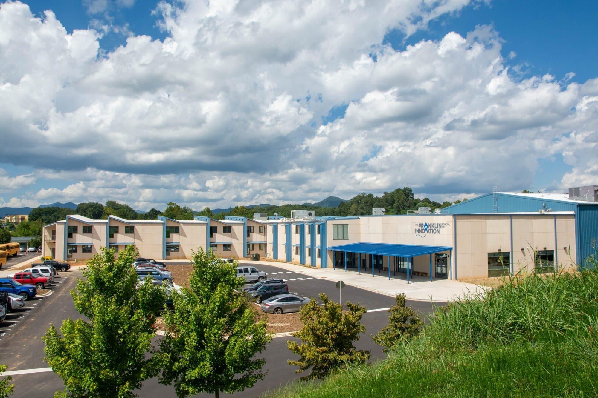 Modern building complex surrounded by trees and a clear blue sky.
