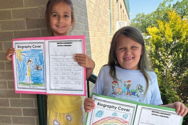 First-graders Melaina Spicciati and Kira Hayden hold their writing projects