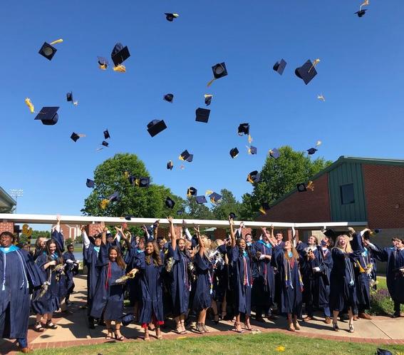Graduates in gowns tossing caps