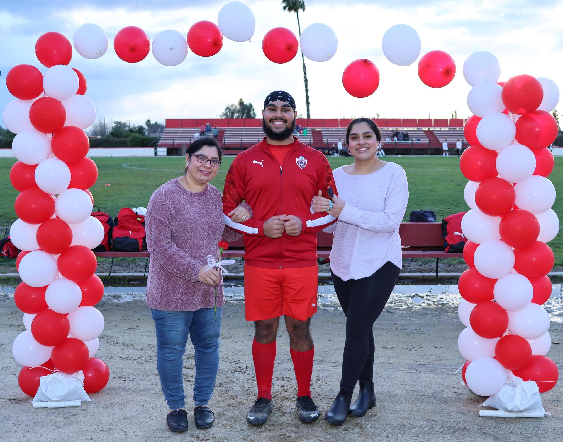 seniors and their escorts posing beneath a balloon arch