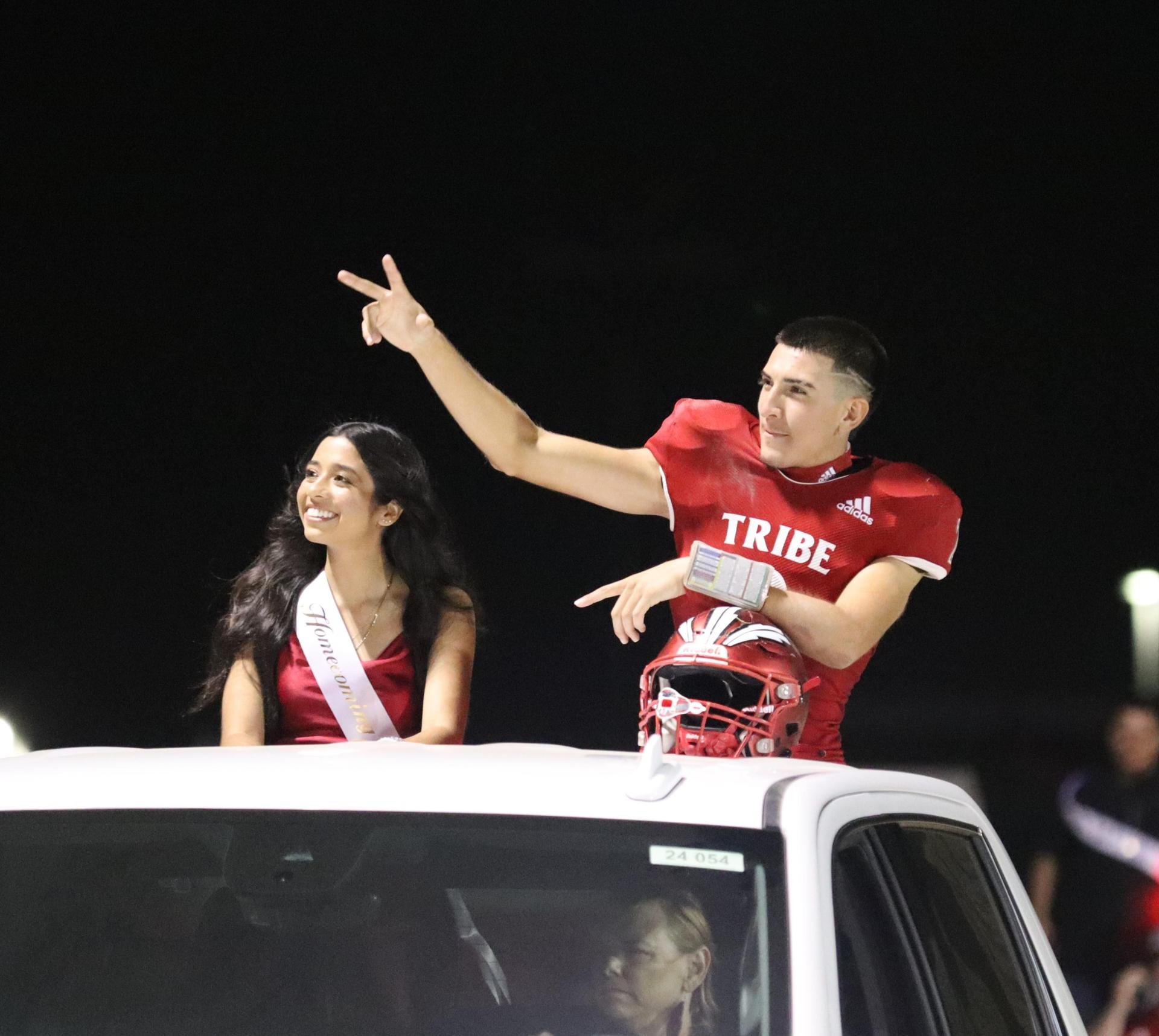 homecoming king and queen candidates entering the stadium in trucks