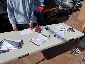 Nashville School of Excellence volunteer collecting parent interest forms during a community outreach event.