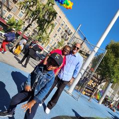 A group of three people poses in a colorful park on a sunny day.
