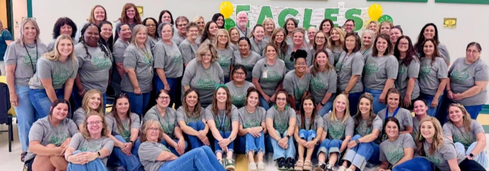 Large group of adults in matching shirts posing together with 'Eagles' decorations.