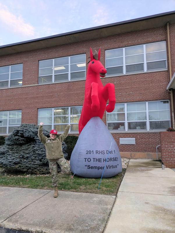 Meghan posing excitedly next to a giant red horse statue.