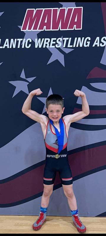 youth wrestler showing off his muscles with medal around neck