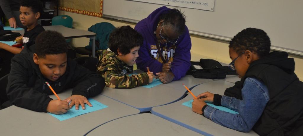 3 boys complete worksheets at desks