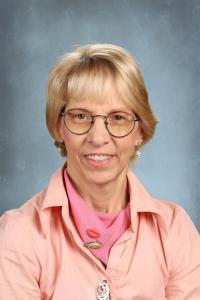 Smiling older woman wearing glasses and a pink blouse.