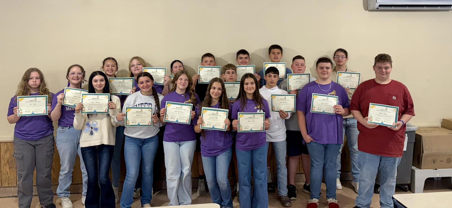 Group of students holding certificates, smiling at the camera.