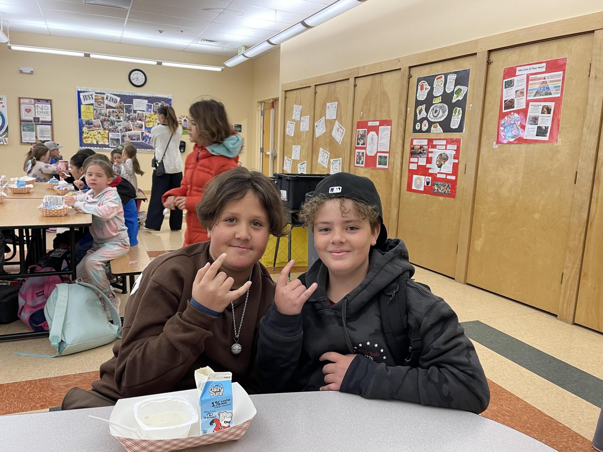 two boys sitting at a table in the cafeteria