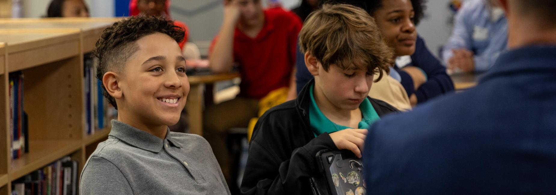 An eighth grade boy smiles while talking to a guest speaker