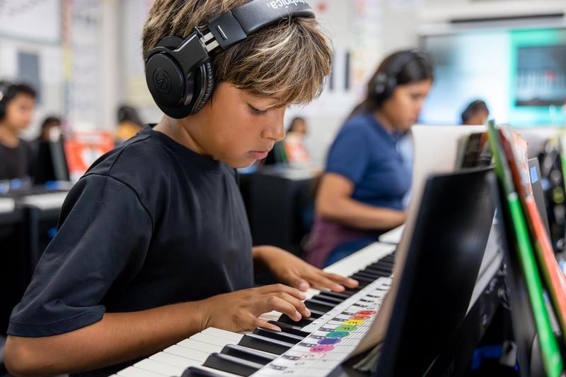 A student at Juliette Low School of the Arts concentrates while practicing piano with headphones during music class.