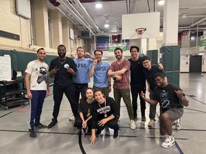 Group of ten people smiling and posing in a gym, with some making peace signs.