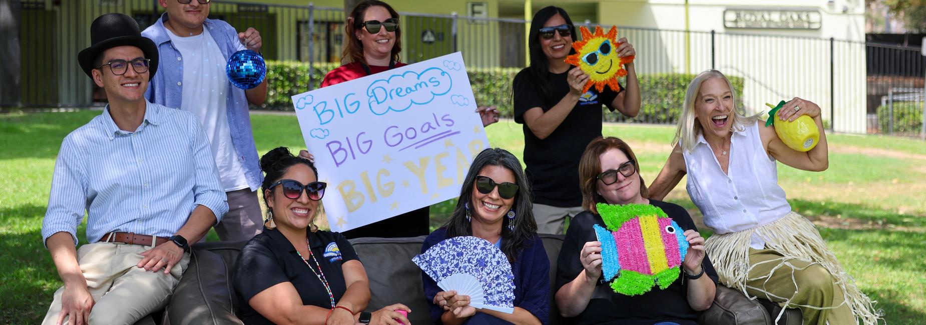 Group of people celebrating with props and signs in a park.