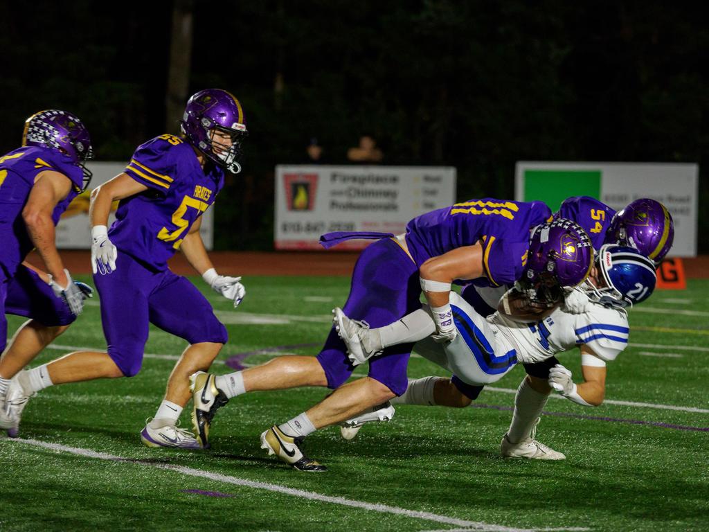 Football players tackling an opponent during a game.