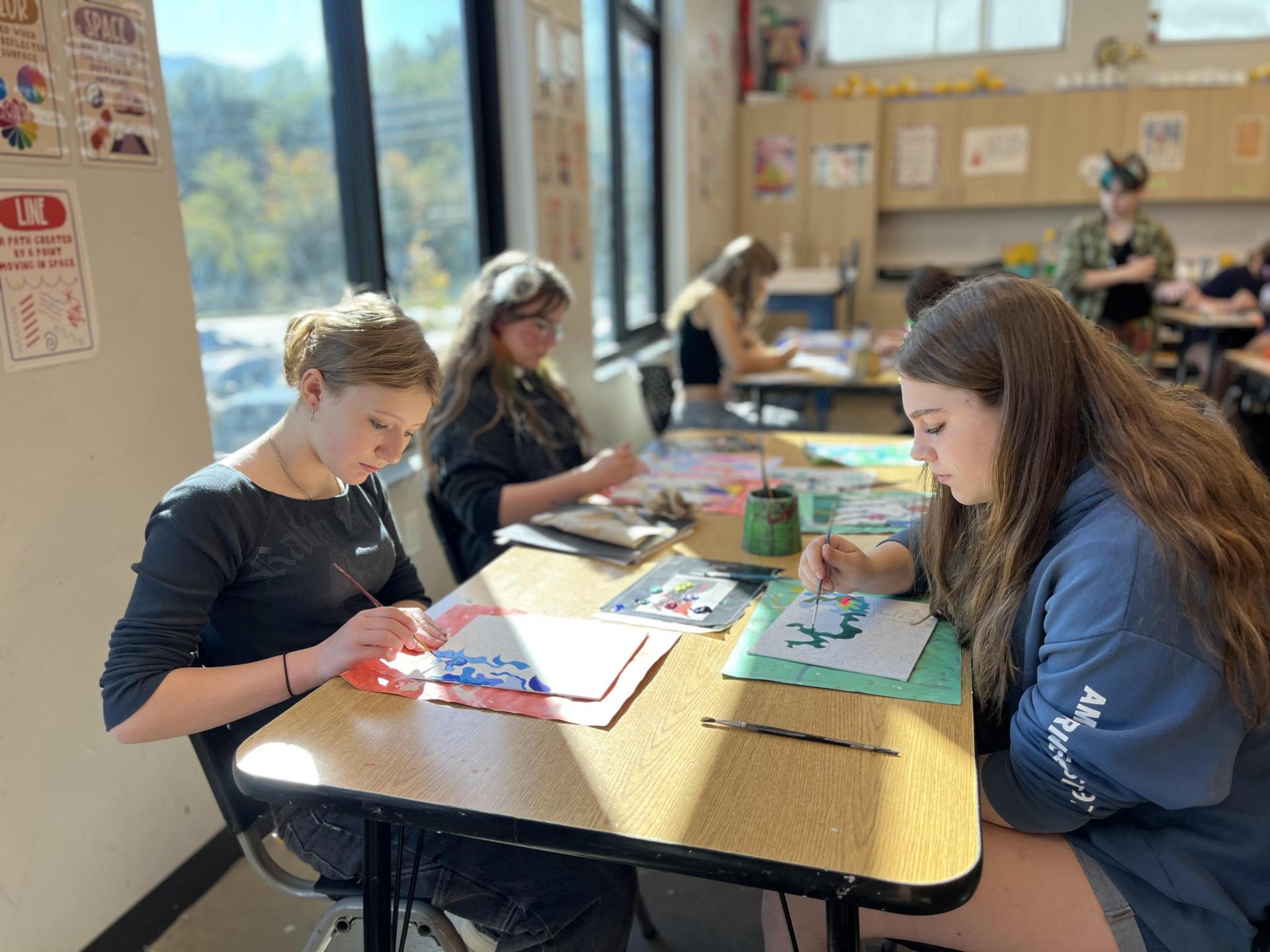 Three students painting with watercolor
