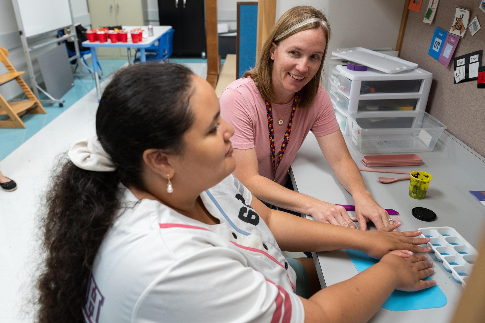 Teacher and student sitting at desk in OT.