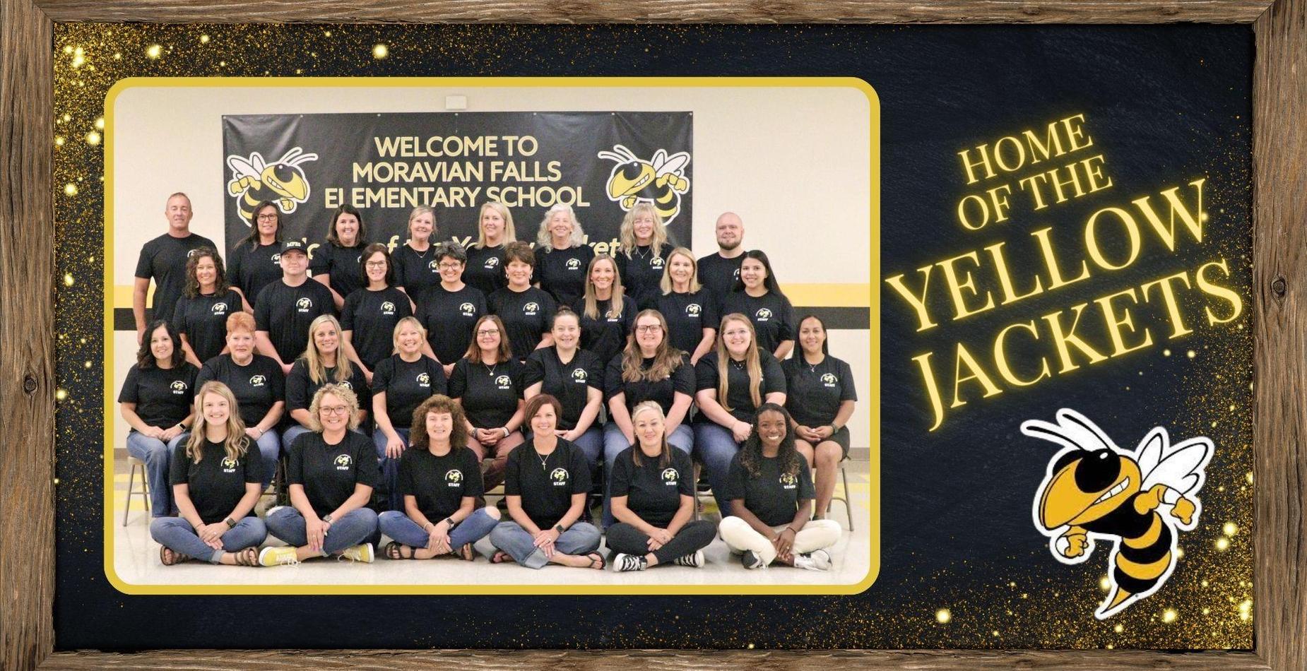 Group of school staff members posing together in front of a welcome banner.  Home of the  Yellow Jackets.
