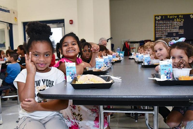 A group of Pre-K students at lunch smiling