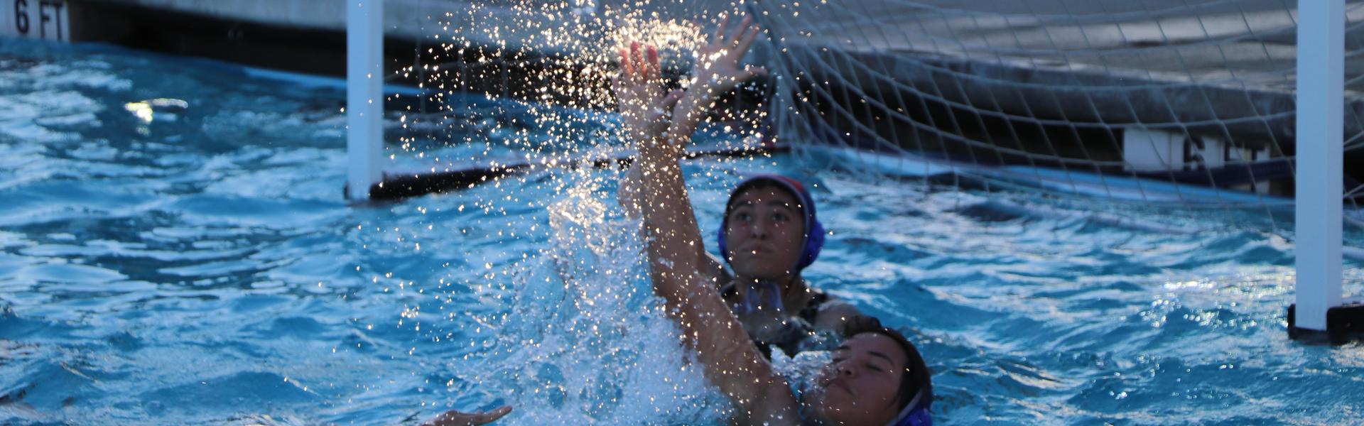 Water polo player making a save in a splashing pool.