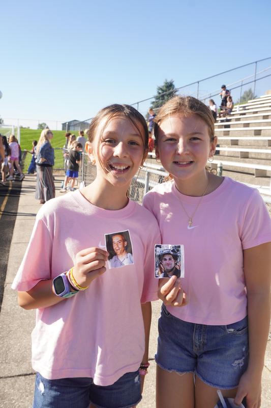 Two students pose for a photo showing the photos they carried with them.