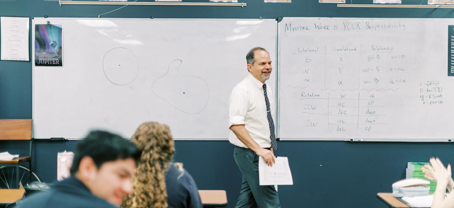Physics teacher smiles as he walks past students in his classroom at Founders Classical Academy &ndash; Leander